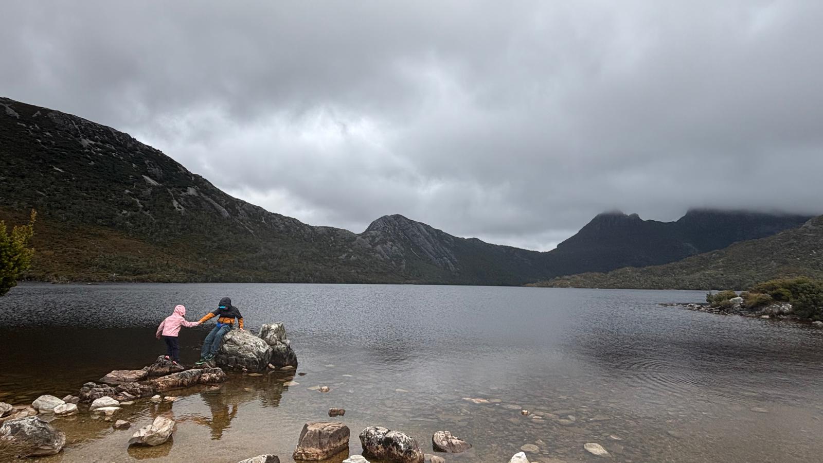 Adult giving a child a hand while crossing the Dove Lake circuit at Cradle Mountain, Tasmania