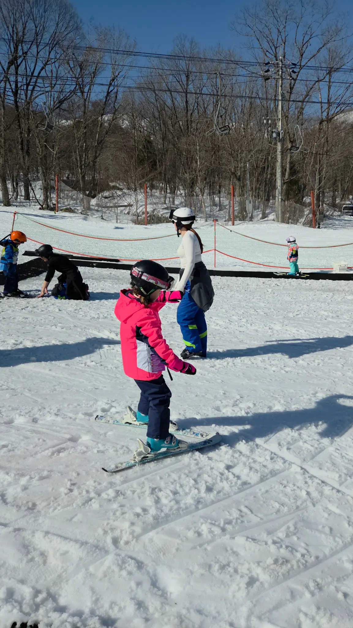 Young child on skis with instructor at Happo-One ski school, Hakuba