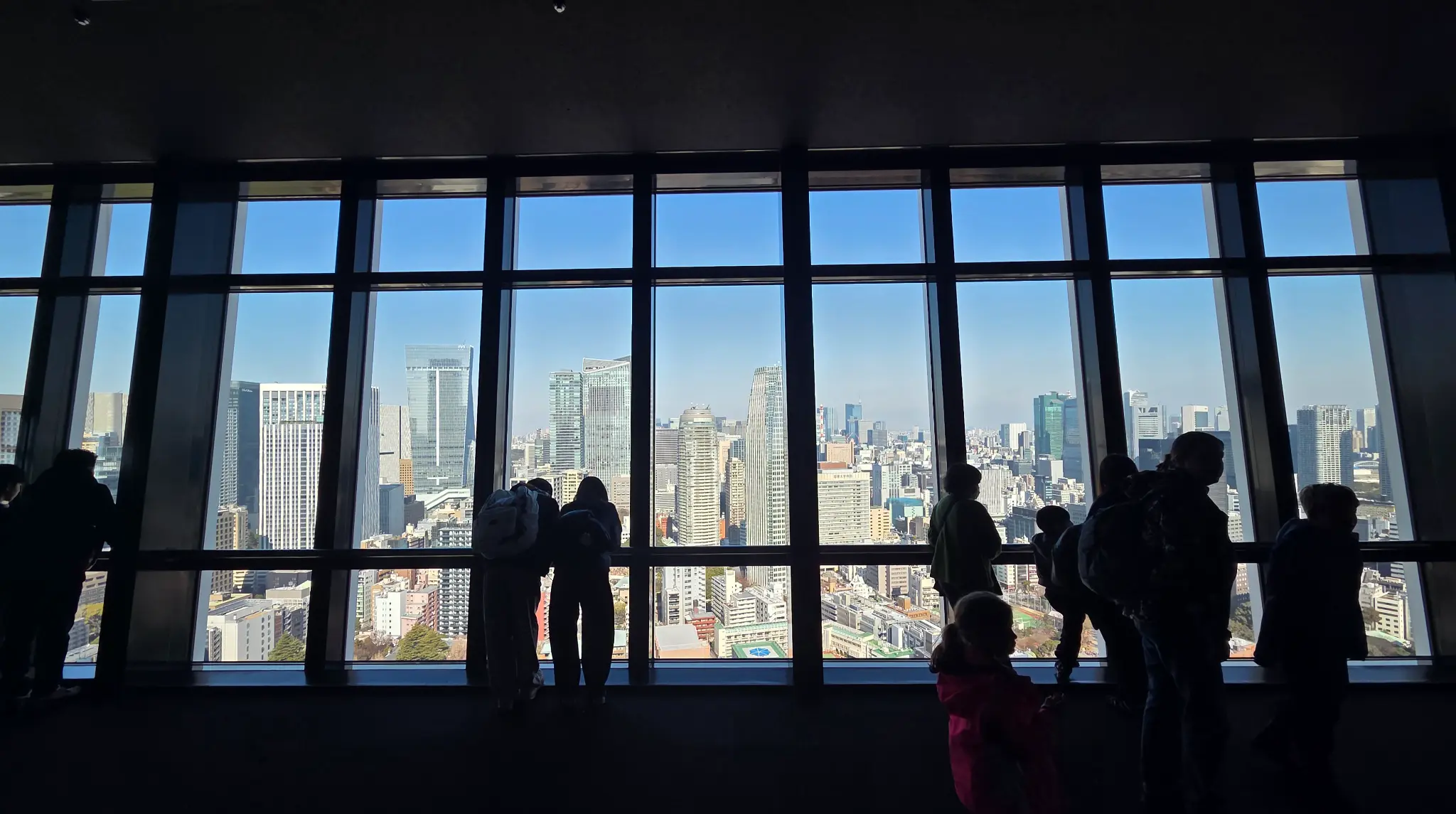 Family silhouettes looking out over the Tokyo skyline from Tokyo Tower's observation deck